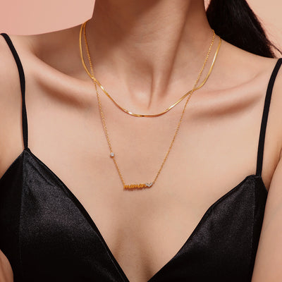 Layered gold maman pendant and herringbone necklace on model