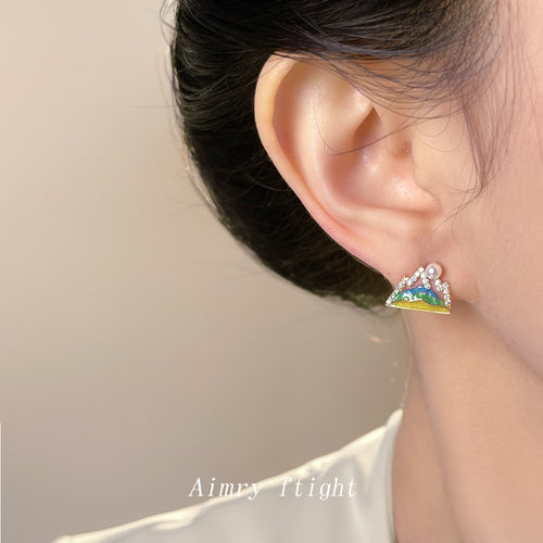 Gold-tone mountain-enamel pearl clear-stone studs shown worn on an ear.