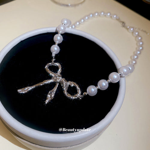 White Pearl Strand Necklace with Silver Tone Bow Center shown in a display view