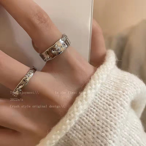 Two silver open zirconia accent rings worn stacked on fingers