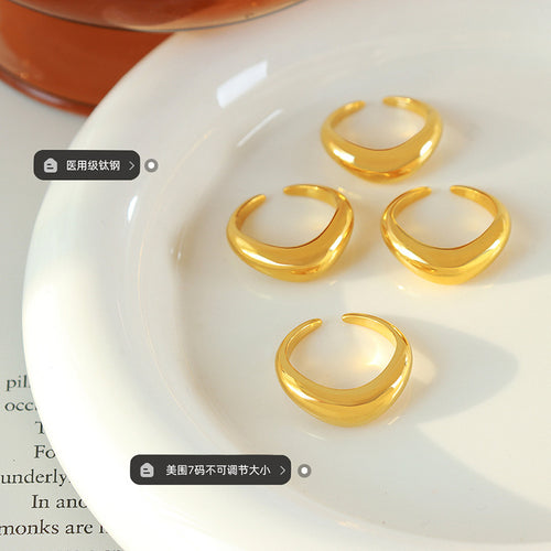 Four gold open dome rings on white plate with size and material labels