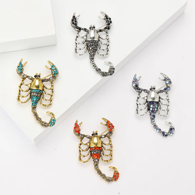 Front view of the crystal scorpion brooch in four colorways with polished metal detail on a white background