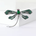 Green Dragonfly Metal Brooch with Dark Green Wings, a Pink Center Stone, and Curved Tail view 1