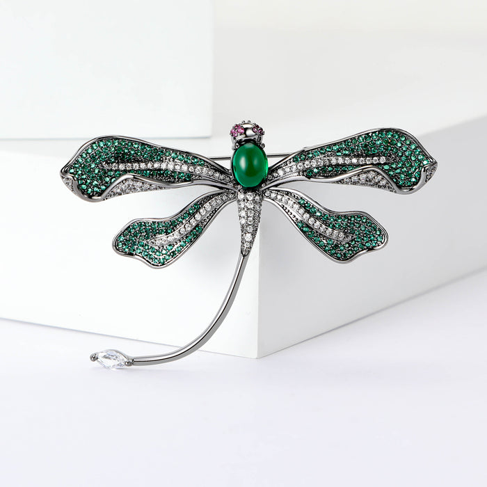 Green Dragonfly Metal Brooch with Dark Green Wings, a Pink Center Stone, and Curved Tail