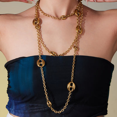 Model wearing long gold coffee bean station necklace layered at chest