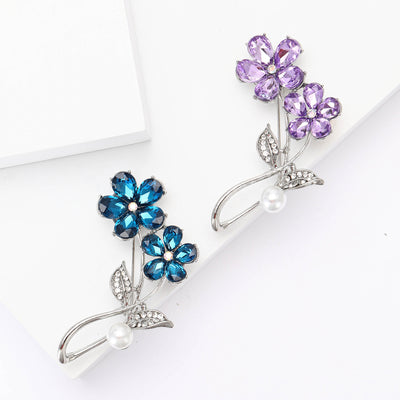 Two crystal blossoms above a curved stem and white pearl shown on a white background.