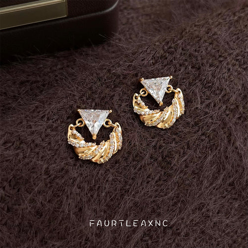 Gold triangle CZ twisted ribbon studs on brown fur surface