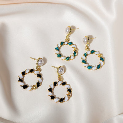 Two pairs of gold pearl studs with teal-white and black-white twisted enamel circles