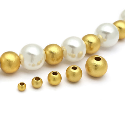 Matte gold-tone spacer bead beads arranged on a light background