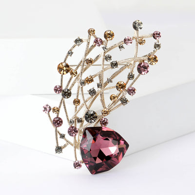 Gold vine branch brooch with purple crystal base on white blocks