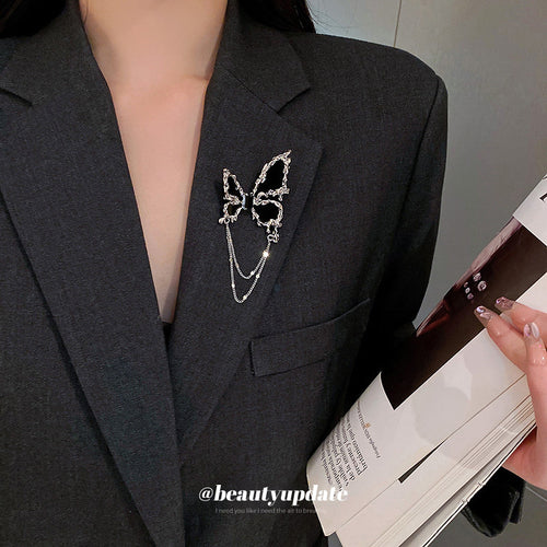 black butterfly brooch with bright silver-tone edging and two chains shown worn in a styled second view