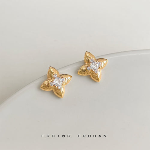 Gold textured four point star crystal studs on white dish