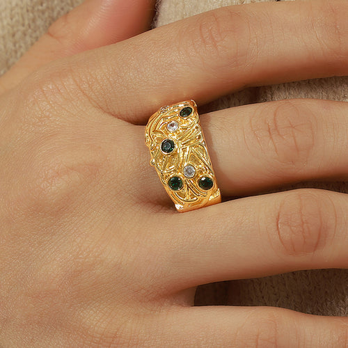 Gold embossed open ring with green and clear stones worn on finger