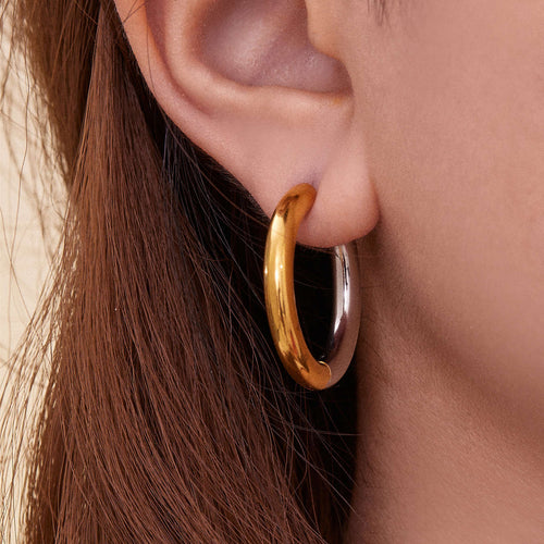 Close ear of large gold-steel two-tone thick huggie hoop