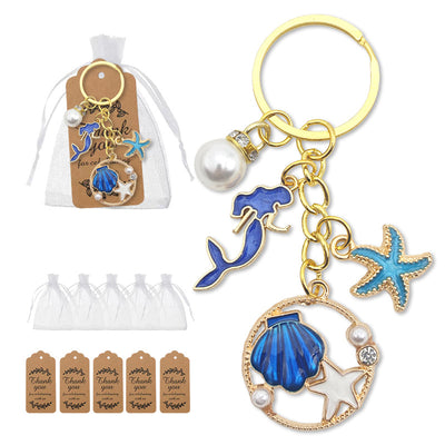 Gold-tone ocean keychain displayed beside a white drawstring bag and printed thank-you tags.