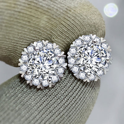 Silver snowflake halo CZ stud earrings held on grey fabric glove
