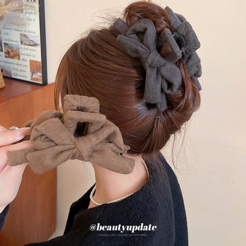 Gray fabric bow claw clip worn in a brunette bun