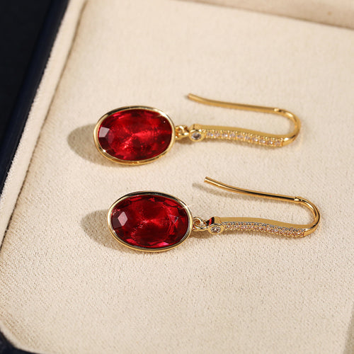 Styled view showing faceted red oval drops on simple gold-tone hooks