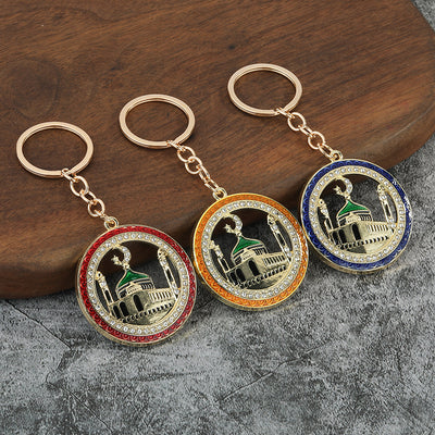 Three round mosque keychains with red, orange, and blue borders on a wooden surface.