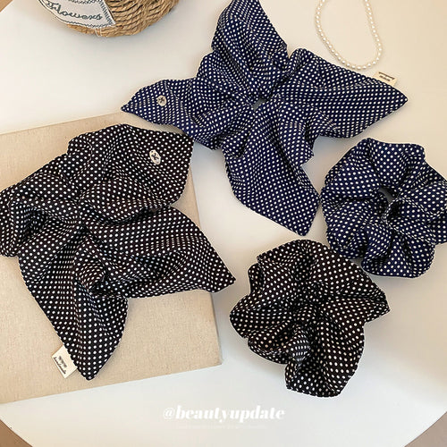 Black and navy polka dot scrunchies and bow styles on white table
