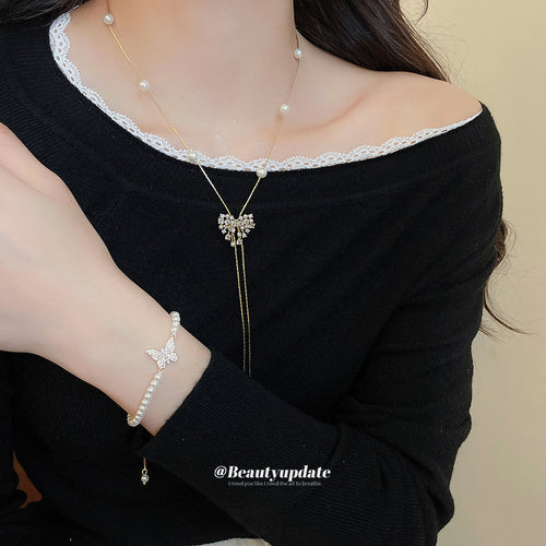 Model wearing gold bow pearl lariat necklace and butterfly pearl bracelet
