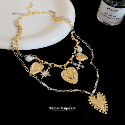 Layered chains with heart, sunburst, star and crystal-like charms displayed from the front.