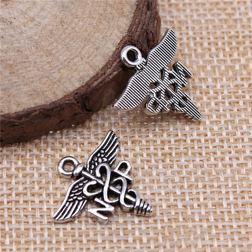 Antique Silver NP caduceus medical symbol charm displayed on a wood and linen setting