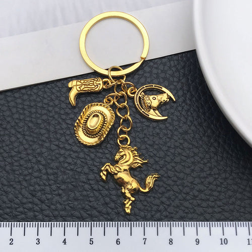 Styled close-up of antique gold and silver western horse hat and boot charm keychains showing colors and surface details