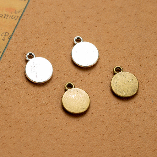 Second product image of the believe coin charm showing a small round tag engraved Believe on a smooth face