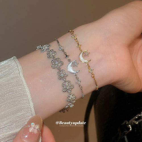 Wrist stack of silver flower bracelet with silver and gold moon star bracelets