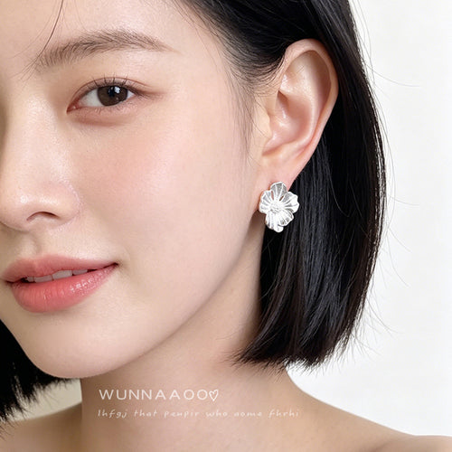 Silver flower stud earring worn on ear front profile