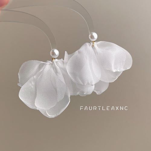 White mesh flower pearl stud earrings held against beige background