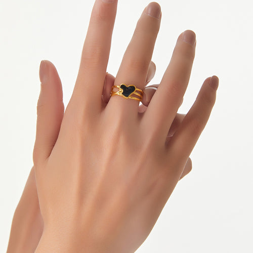 Hand wearing gold black heart oil drip adjustable ring on middle finger