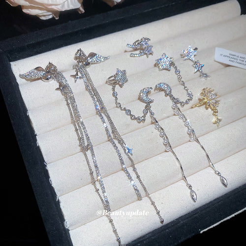 Styled view of silver and gold tone star moon ear cuffs with chain drops