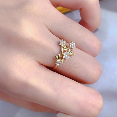 Gold flower branch clear stone ring worn on finger top view
