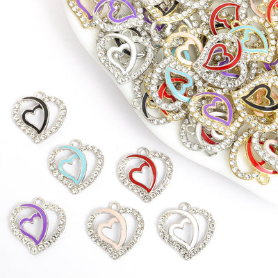 Assorted crystal double heart charms arranged beside a tray on white