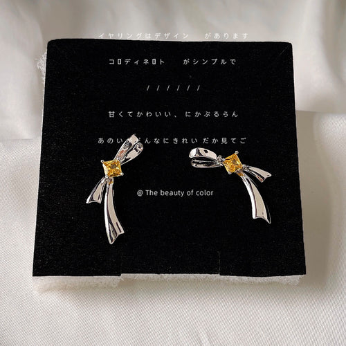 Silver bow studs with yellow stones on black card
