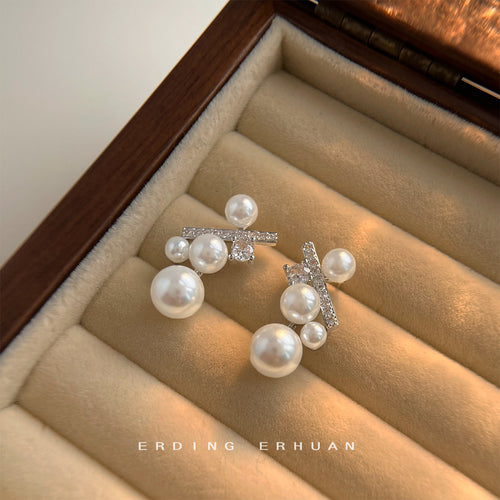 Pearl percent symbol studs displayed in beige jewelry box