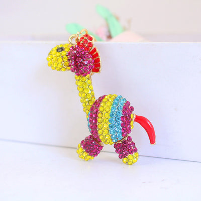 Front view of a yellow long-neck animal charm with pink and blue rhinestone stripes.