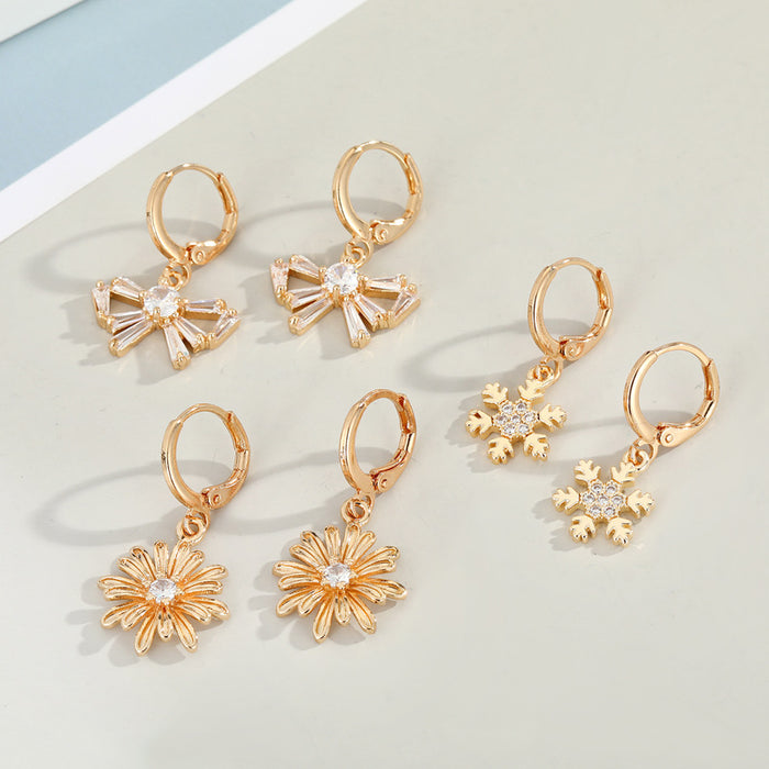 Gold Tone Huggie Earrings with Crystal Daisy and Bow Charm Drops