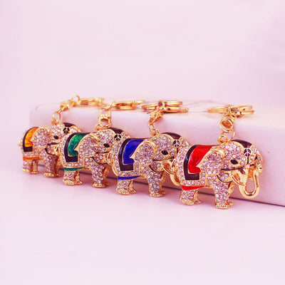 Four gold-tone elephant keychains with red, blue, green, and gold saddle panels.