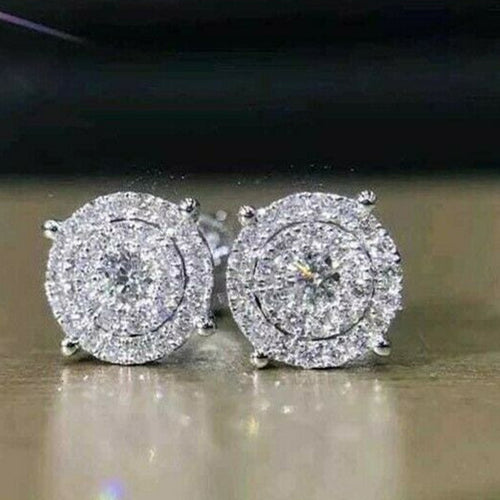 Round cluster halo studs close-up on warm reflective table