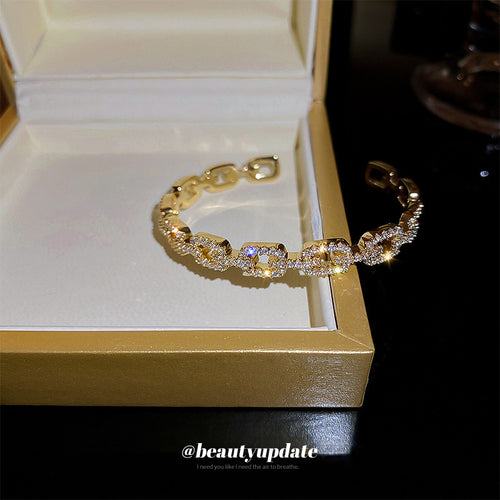 gold-tone open cuff with crystal-covered buckle-shaped links shown in the first close product view