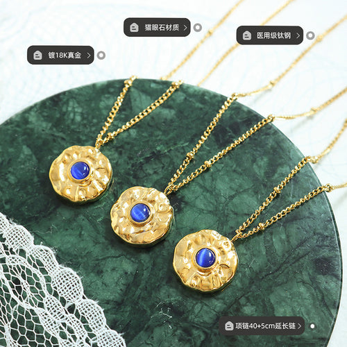 Three gold cat-eye pendants on green marble with material labels