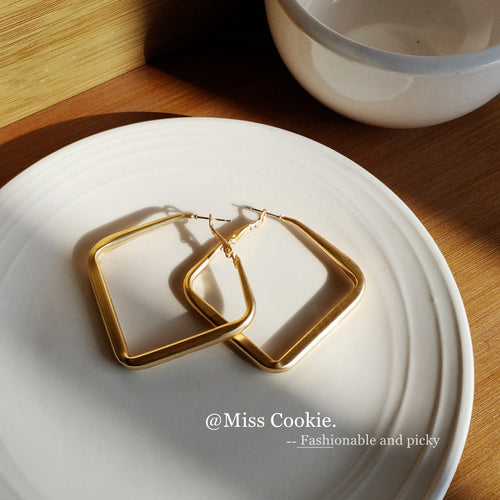 Matte gold square hoops crossed on white ridged plate