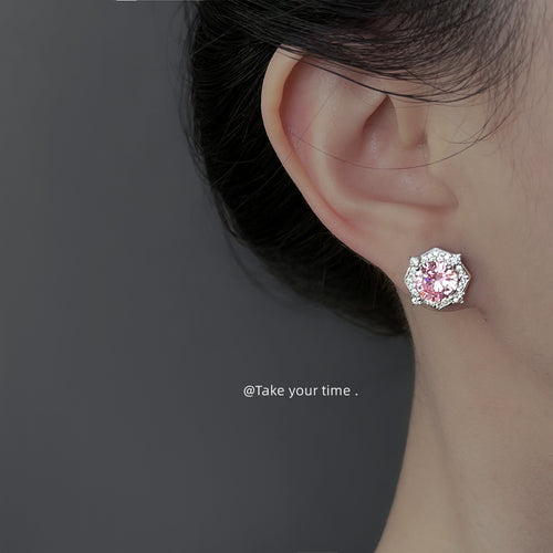 Pink halo CZ stud worn on ear against gray background