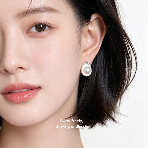 Silver-tone irregular oval white-pearlescent studs shown worn on an ear.