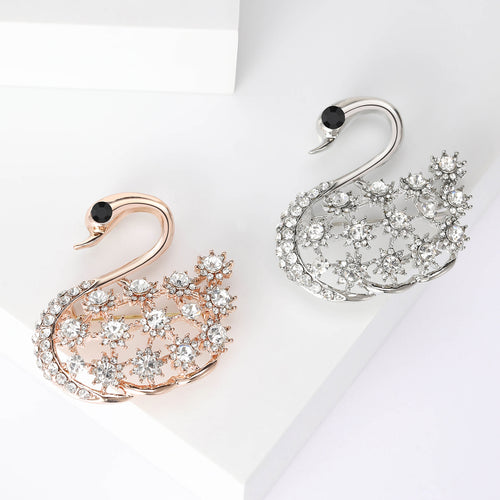Rose gold and silver rhinestone swan brooches on white blocks