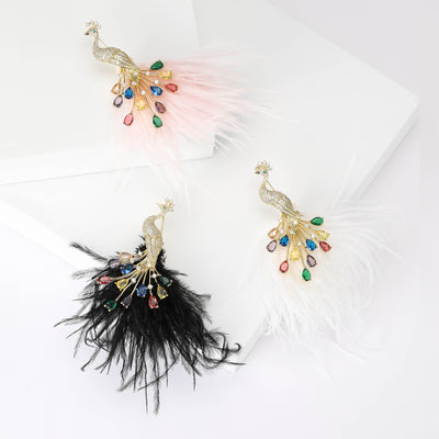 Three peacock feather brooches with pink white and black plumes