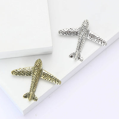 Gold and silver hammered airplane brooches on white steps